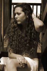 Young woman looking away while sitting in kitchen