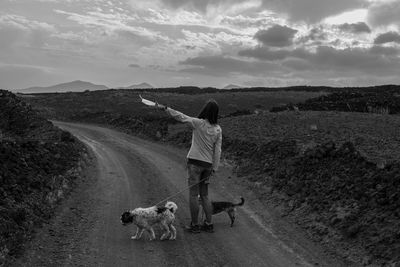 View of woman with dogs on a road.