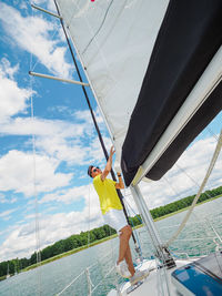Handsome person raise the sail on a sailing yacht, summer vacations on sailboat person