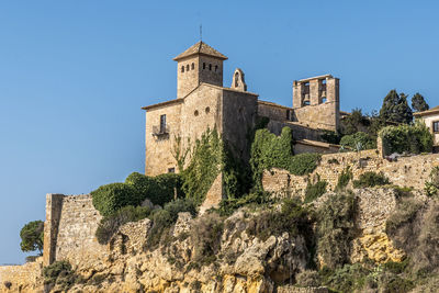 Low angle view of castillo tamarit on cliff against clear sky