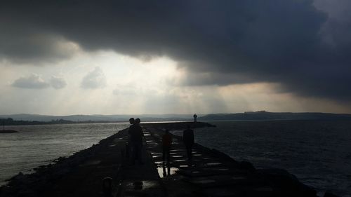 Pier on sea against cloudy sky