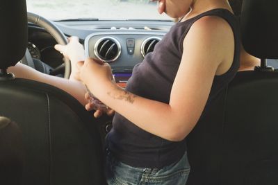 Midsection of boy standing in car