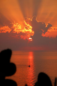 Silhouette people by sea against sky during sunset