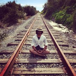 Man with hands clasped sitting on railroad track