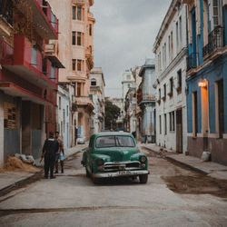 Rear view of man walking on street amidst buildings