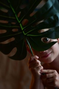 Close-up portrait of smiling child looking through leaves