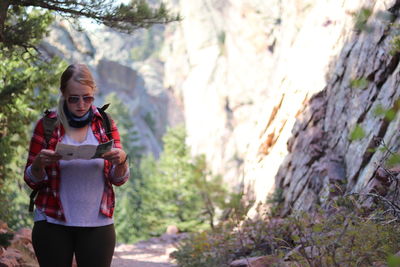 A young woman reads a map while hiking through the mountains