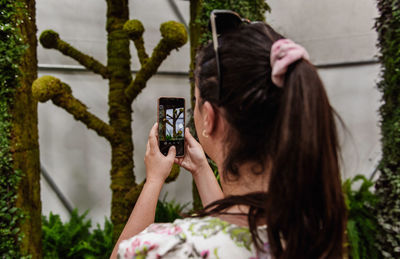 Rear view selective focus photo of woman taking photos of plants in botanical garden