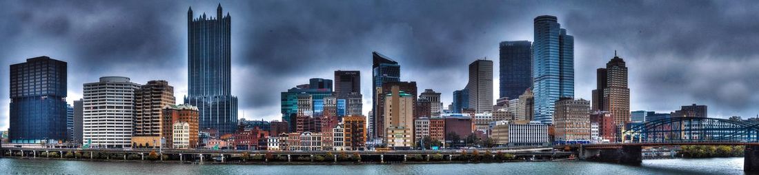 City at waterfront against cloudy sky