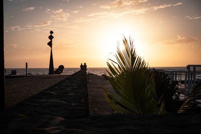 Silhouette people on beach against sky during sunset