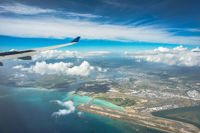 An aerial vista captures oahu hawaii with the airport below framed by billowing clouds. 