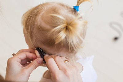 Close-up of mother adjusting hearing aid of daughter