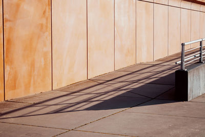 Shadow of railing on footpath against wall