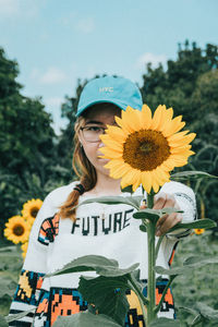 Full length of person holding sunflower against sky