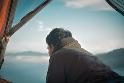 Side view of man wearing warm clothing while sitting in tent