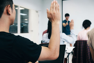 Close-up of man raising hand in classroom