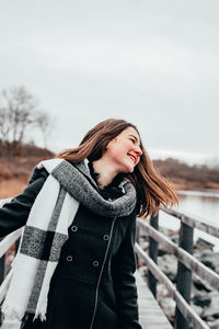 Young woman standing on snow against sky