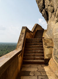 Staircase leading towards sea against sky