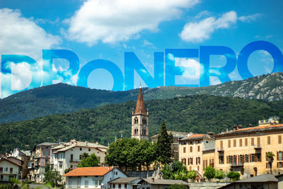 Information sign by buildings in town against sky