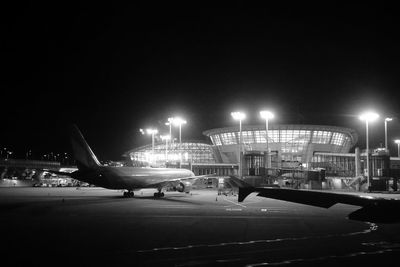 Airplane on airport runway against sky at night