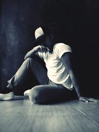 Side view of young man sitting on floor