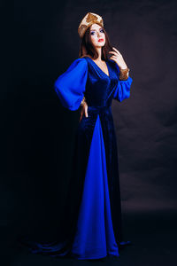 Portrait of beautiful woman in traditional clothing standing against black background