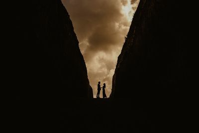 Silhouette couple standing against sky during sunset