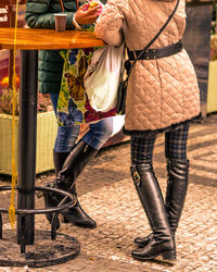 Low section of friends standing by table at sidewalk cafe