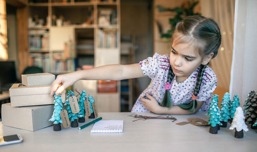 Girl preparing diy gifts and signing tags to family for christmas, handmade, zero waste holidays