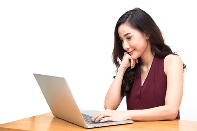 Young woman using phone while sitting on white background