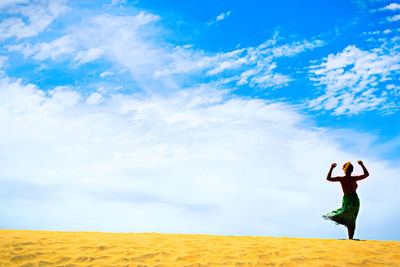 Full length of woman standing on desert against sky