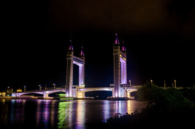 Illuminated bridge over river at night