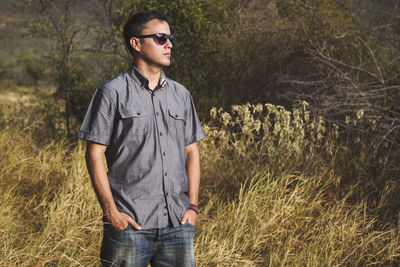 Young man wearing sunglasses standing on land