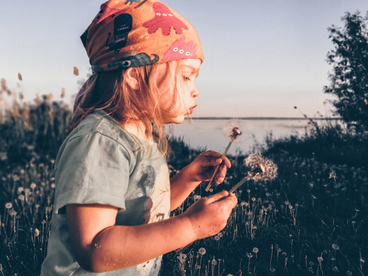 one person, nature, adult, plant, women, land, sky, side view, activity, female, outdoors, leisure activity, holding, young adult, child, sunlight, lifestyles, person, sunset, childhood, grass, waist up, fun, water, field, landscape, clothing, rural scene, beauty in nature, day, summer, blond hair, looking, hairstyle, technology