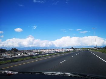 Cars on road against sky seen through car windshield