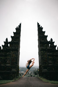 Low angle view of woman dancing in entrance against sky