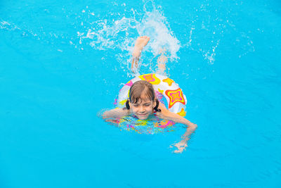 High angle view of girl swimming with inflatable ring in pool