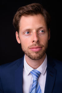 Portrait of young man against black background