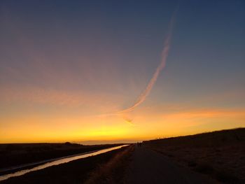 Road amidst silhouette landscape against sky during sunset