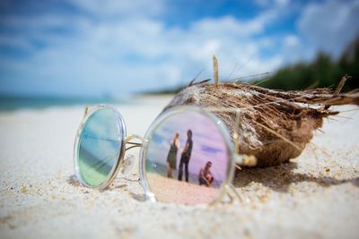 Close-up of sunglasses with reflection of people on beach 