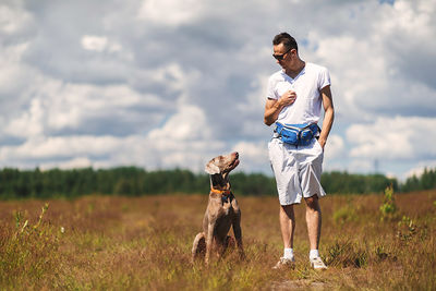 Full length of man with dog standing on field