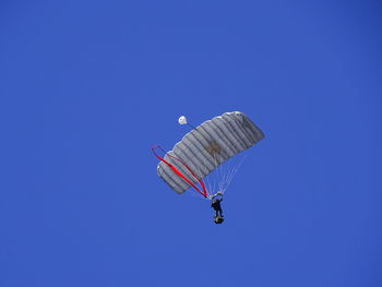 Low angle view of person paragliding against clear blue sky