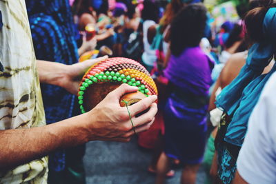 Cropped hand of man holding musical instrument during carnival