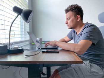 Side view of man working from home using laptop