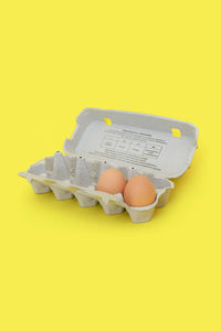 High angle view of eggs in container against yellow background