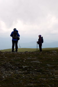 Rear view of woman photographing on landscape against sky