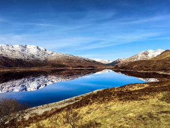 Scenic view of lake and mountains against blue sky