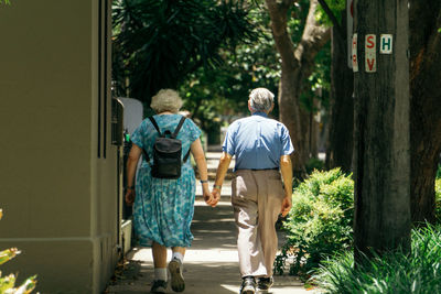 Rear view of men walking on road amidst trees