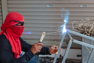 Midsection of man holding illuminated while standing on metal
