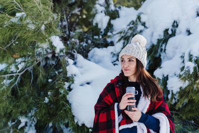 Portrait of young woman using smart phone during winter